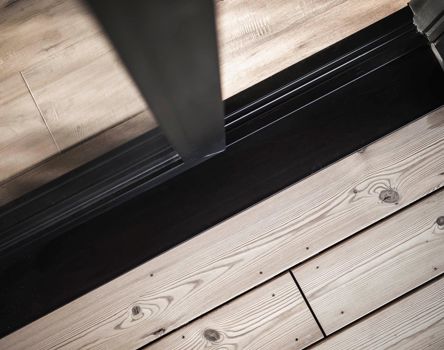 Detailaufnahme eines Türübergangs zwischen Innen- und Außenseite mit Holz- und Metallelementen.