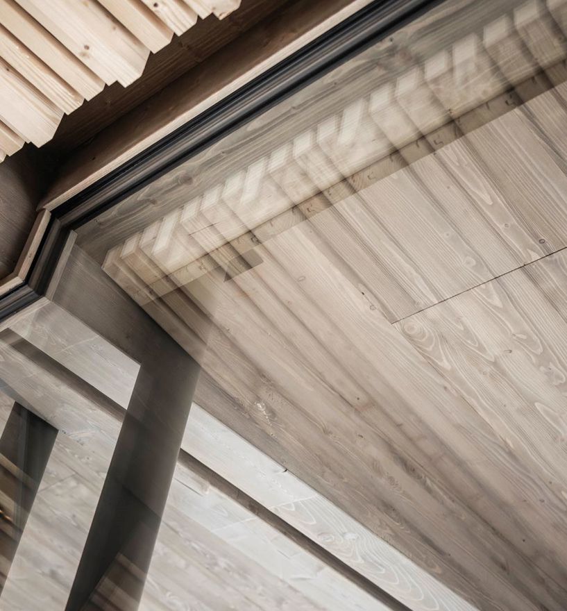 Detailansicht von Holzoberflächen und Fenstern, die das reflektierte Holz zeigen.
