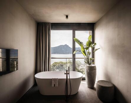 Minimalistischer Badbereich mit rahmenloser Verglasung und Seeblick im Hotel Cape of Sense, Gardasee