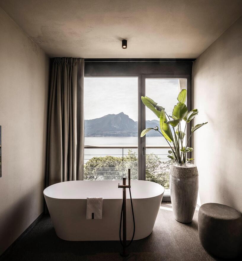 Minimalistischer Badbereich mit rahmenloser Verglasung und Seeblick im Hotel Cape of Sense, Gardasee