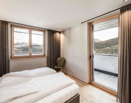 Una camera d'albergo con balcone e finestre in legno Climatop 92