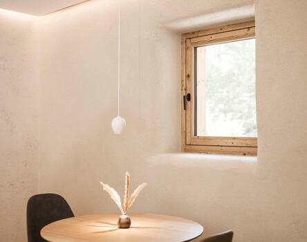 Rustikaler Gastraum mit rundem Tisch und Fensterlicht, Restaurant Drena
