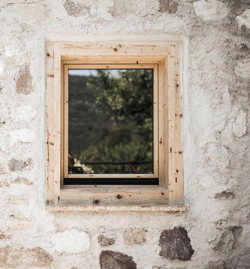 Kleines Fenster aus Altholz in der Steinfassade, La Casina