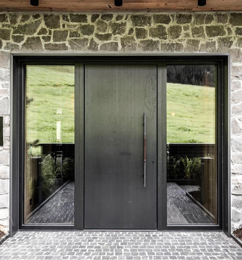 Moderna porta d'ingresso con elementi vetrati su facciata in pietra — linee pulite, materiali pregiati